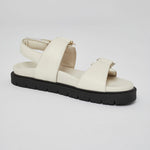 Close-up of white Barna leather sandal with gold buckle and back strap