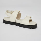 Close-up of white Barna leather sandal with gold buckle and back strap