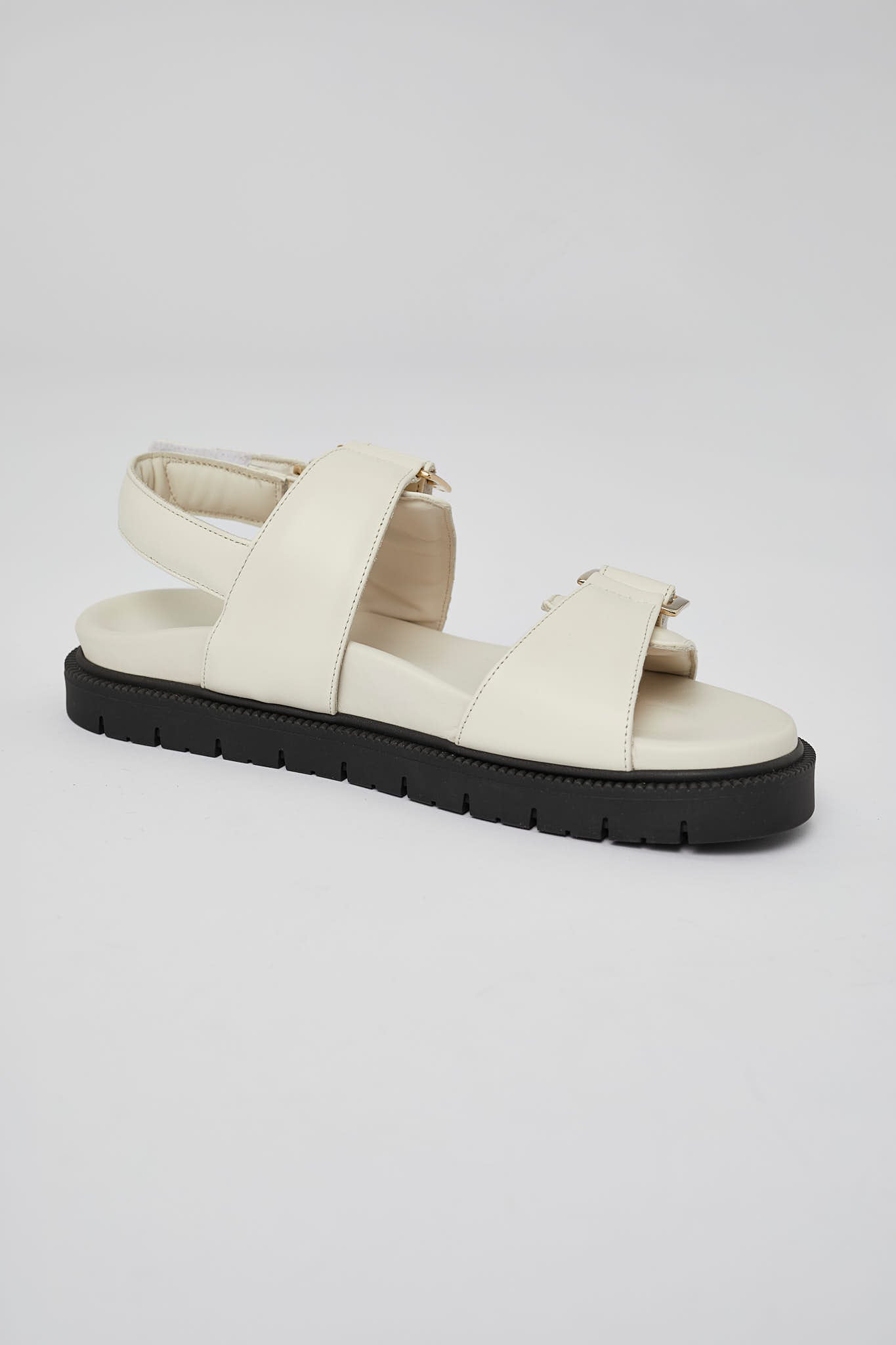 Close-up of white Barna leather sandal with gold buckle and back strap